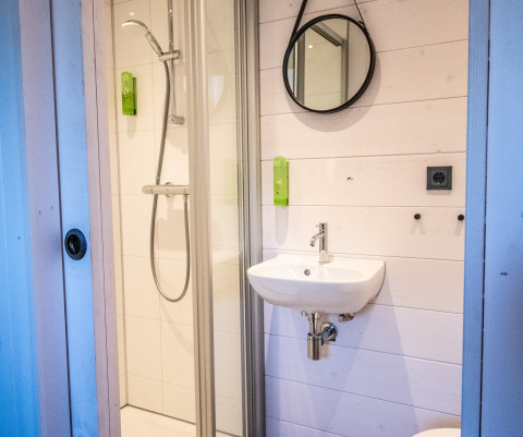 Modernes Campingbad bei Erfgoed Bossem - Sterrenkubussen Twente mit Dusche, Spiegel und Waschbecken.