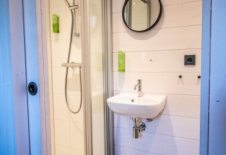 Salle de bain moderne glamping à Erfgoed Bossem - Sterrenkubussen Twente avec douche, miroir et lavabo.