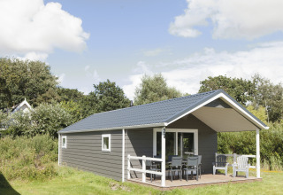 Strand49 - Strandlodges & Cabins Noord-Holland: lodge glamping con patio, sedie e ambiente naturale verde.