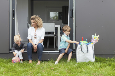Familie nyder tid foran Strand49 glamping lodge i Noord-Holland med børn og legeudstyr på græsset.