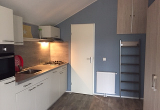 Moderne Campingküche in Strand49 - Strandlodges & Cabins Noord-Holland mit Herd und Schränken.