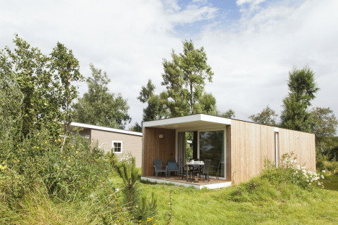 Lodge en bois moderne pour glamping à Strand49 Noord-Holland, terrasse entourée de verdure et nature.