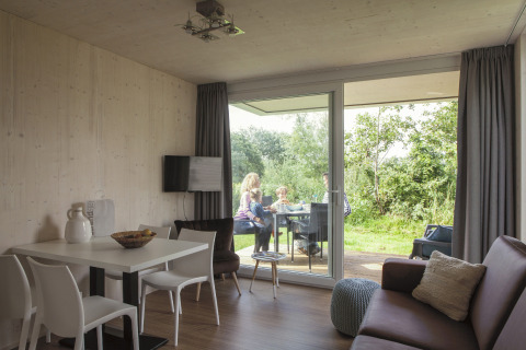 Strand49 glamping accommodatie in Noord-Holland met gezin dat buiten eet op het terras bij het groen.