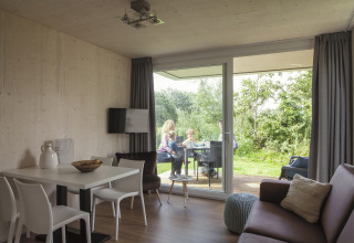 Gemütliche Strand49 Strandlodges & Cabins Noord-Holland, Familie genießt Essen im Gartenbereich.