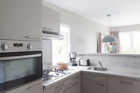 Cuisine moderne à Strand49 lodge Noord-Holland avec four, cuisinière, évier, cafetière et lumière naturelle.