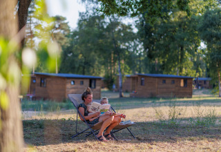 Frau und Kind entspannen und lesen draußen bei Camping Huttopia De Meinweg - Glamping Limburg in den Niederlanden.