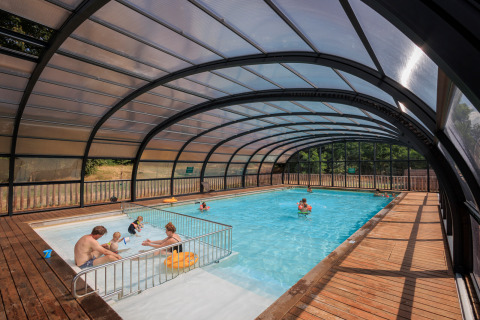 Piscina cubierta con familias disfrutando del agua en Camping Huttopia De Meinweg Glamping Limburg.