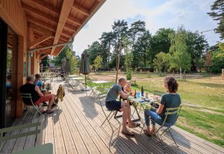 Buiten dineren bij Camping Huttopia De Meinweg - Glamping Limburg met gasten en uitzicht op natuur.