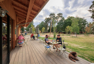 Udendørs terrasse på Camping Huttopia De Meinweg Glamping Limburg med gæster og natur i baggrunden.