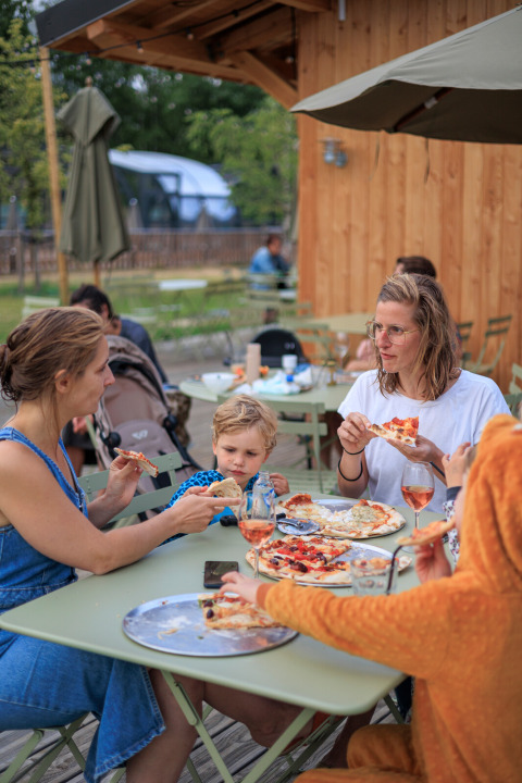 Gezin eet pizza buiten bij Camping Huttopia De Meinweg - Glamping Limburg, Nederland.