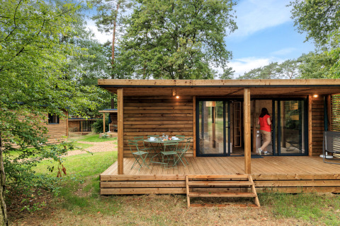 Cabane en bois au Camping Huttopia De Meinweg - Glamping Limburg avec terrasse et table extérieure en pleine nature.