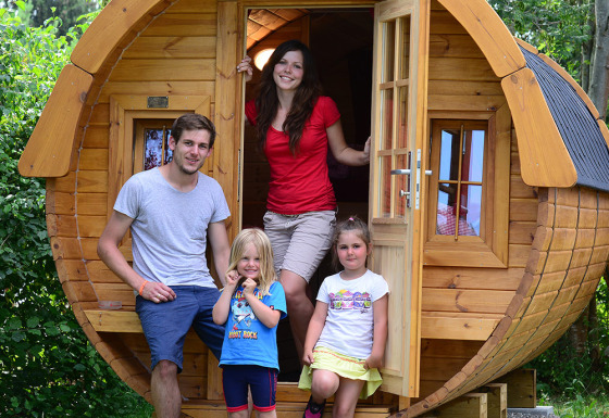 Famille devant une cabane glamping en forme de tonneau au Camping Heidehof, Glamping Baden-Württemberg.