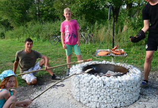 Familie genießt gemeinsames Grillen an einer Feuerstelle auf dem Camping Heidehof - Glamping Baden-Württemberg.