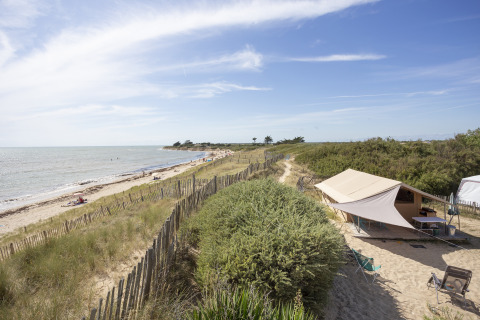 Glamping ved stranden på Huttopia Côte Sauvage - Île de Ré med telt og udsigt over sandklitter og hav.