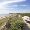 Glamping by the beach at Huttopia Côte Sauvage - Île de Ré with a tent, sand dunes, and a scenic coast view.
