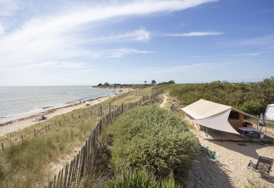 Glamping sur la plage à Huttopia Côte Sauvage - Île de Ré avec tente, dunes de sable et vue sur l’océan.