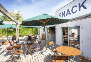 Outdoor snack area with green umbrellas at Huttopia Côte Sauvage - Ile de Ré glamping in Nouvelle-Aquitaine.