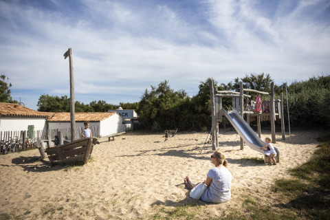 Children and adults playing on a sandy playground at Huttopia Côte Sauvage - Ile de Ré glamping, Nouvelle-Aquitaine.
