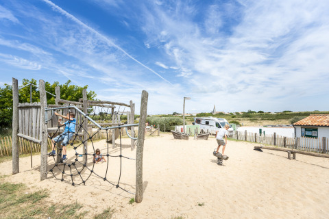 Des enfants jouent sur une aire de jeux en sable au Huttopia Côte Sauvage - Ile de Ré dans la région Nouvelle-Aquitaine.