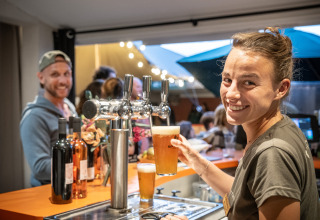 Mujer sirviendo cerveza de barril en el bar de Huttopia Côte Sauvage - Ile de Ré, glamping en Nouvelle-Aquitaine, Francia.