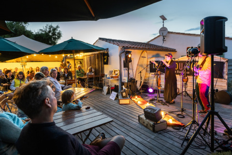Concierto al aire libre en Huttopia Côte Sauvage - Ile de Ré glamping, huéspedes disfrutan música en vivo.