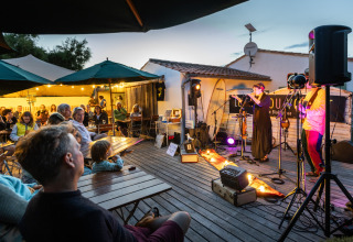 Udendørs live koncert på Huttopia Côte Sauvage - Ile de Ré glamping med publikum under paraplyer.