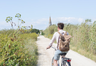 Een persoon fietst over een zandpad bij Huttopia Côte Sauvage - Ile de Ré - Glamping Nouvelle-Aquitaine.