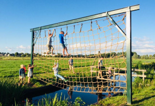 Des enfants escaladent un grand filet en plein air à Boerderij De Boerinn – Safaritenten Utrecht glamping.