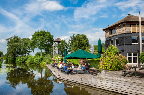 Buiten terras aan het water bij Boerderij De Boerinn – Safaritenten Utrecht met groene en bloemrijke omgeving.