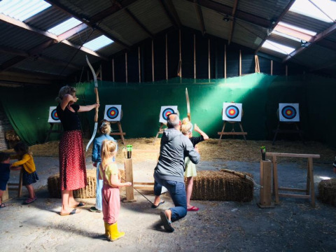 Famiglia prova il tiro con l'arco al coperto a Boerderij De Boerinn Safaritenten Utrecht, glamping in Olanda.
