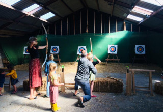Familie übt Bogenschießen in der Halle bei Boerderij De Boerinn Safaritenten Utrecht, Camping in Holland.