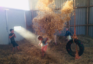 Des enfants jouent dans une grange pleine de paille à Boerderij De Boerinn, glamping à Utrecht, Pays-Bas.