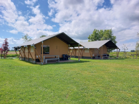Two safari tents on a green lawn at Boerderij De Boerinn – Safaritenten Utrecht, beneath a blue sky.