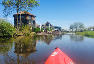 Rode kajak op een rivier, varend naar glamping Boerderij De Boerinn met terras in Utrecht, Nederland.