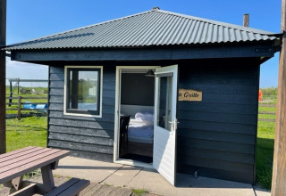 Black glamping cabin at Boerderij De Boerinn – Safaritenten Utrecht with open door and wooden picnic table.