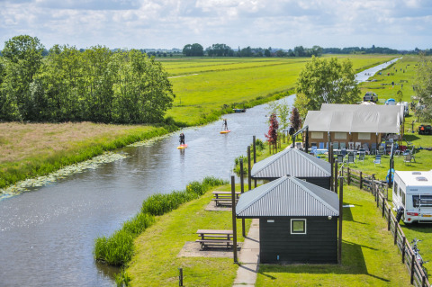Glamping en Boerderij De Boerinn – Safaritenten Utrecht con cabañas, tiendas, caravana y canal en entorno verde.