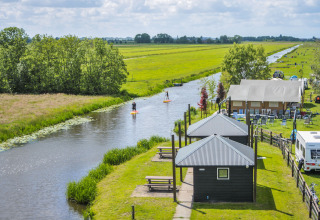 Glamping bij Boerderij De Boerinn – Safaritenten Utrecht met huisjes, tenten, caravan en een kanaal in het groen.