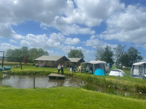 Glamping ved Boerderij De Boerinn – Safaritenten Utrecht med telte, hytter og folk ved en dam.