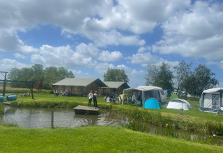Glamping à Boerderij De Boerinn – Safaritenten Utrecht, tentes, cabanes et personnes près d'un étang.