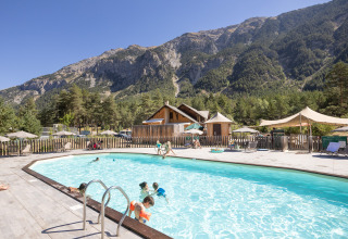 Famiglie si godono la piscina a Huttopia La Clarée - Glamping Hautes-Alpes con vista sulle montagne.