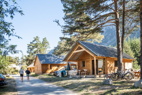 Holzhütten und entspannte Gäste im Huttopia La Clarée - Glamping Hautes-Alpes, ideal für Naturfreunde.