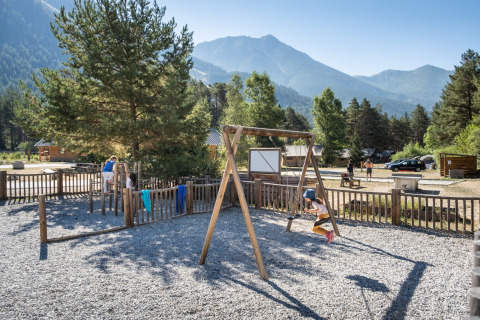 Kinder spielen auf einem Spielplatz mit Schaukel bei Huttopia La Clarée Glamping Hautes-Alpes in den Alpen.