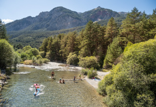 Menschen entspannen am Fluss und genießen die Natur bei Huttopia La Clarée - Glamping Hautes-Alpes im Gebirge.