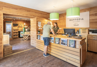 Receptie van Huttopia La Clarée Glamping Hautes-Alpes met houten interieur en gast bij de balie.