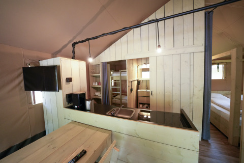 Vue intérieure d’un hébergement glamping au Serengeti Park Tongasoa Lodges, Nedersaksen, avec décoration en bois et équipements modernes.