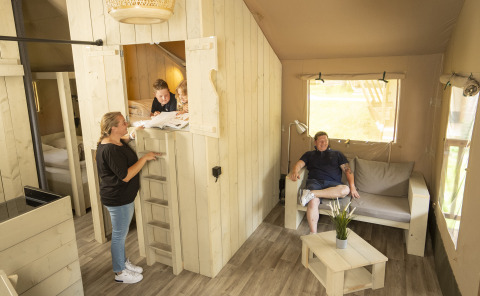Family relaxing in a cozy glamping accommodation at Serengeti Park Tongasoa Lodges, Lower Saxony, Germany.