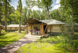 Familia relajándose frente a tienda glamping en Serengeti Park - Tongasoa Lodges, rodeados de naturaleza, Baja Sajonia.