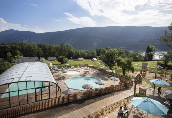 Udsigt over Huttopia Lac d'Aiguebelette glamping med swimmingpool, grønne områder og bakker i Savoie.