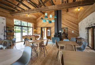 Sala común en Huttopia Lac d'Aiguebelette, con muebles de madera, lámparas azules y futbolín.