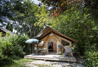 Glamping accommodation at Huttopia Lac d'Aiguebelette - Glamping Savoie with deck, chairs, and forest view.